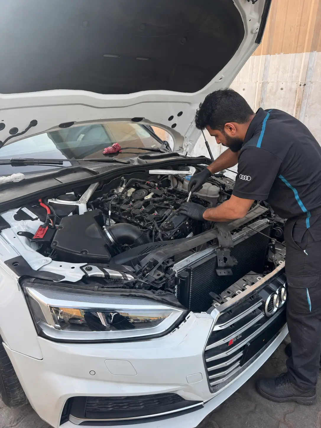 فني يعمل بأداة يدوية داخل حجرة محرك أودي بيضاء