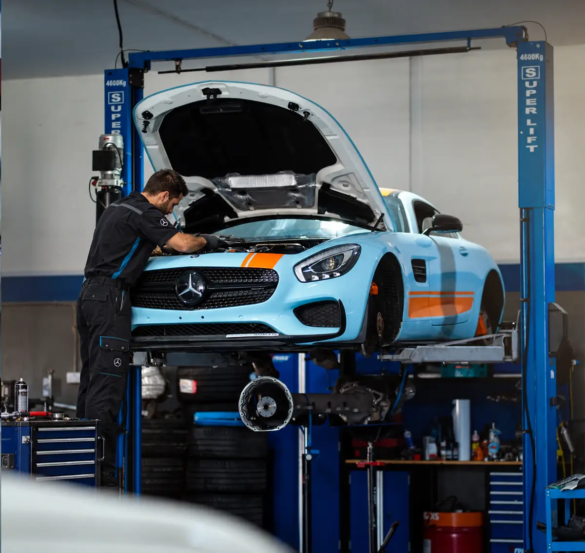 فني يعمل على محرك مرسيدس AMG GT زرقاء مرفوعة على رافعة